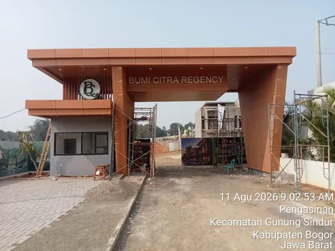 Foto lapangan 11 Agustus 2026: gerbang masuk kawasan dan jalan paving yang sedang dikerjakan